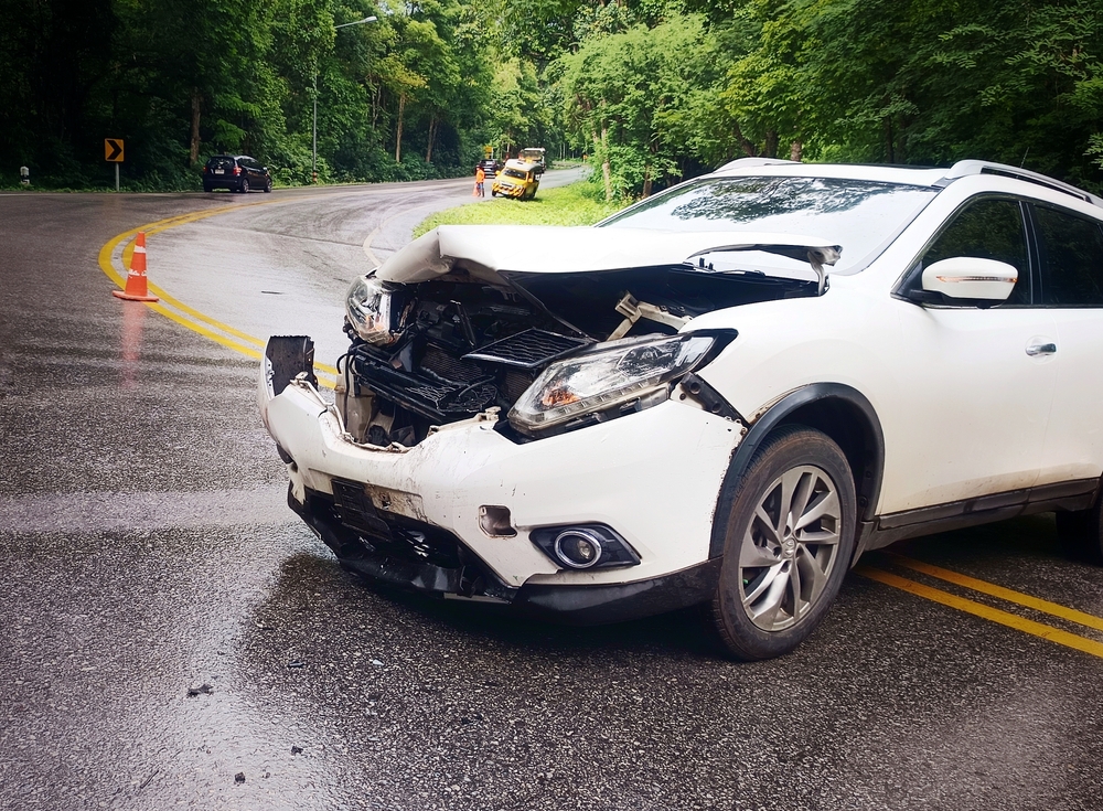 White car damaged in an accident on a curved road